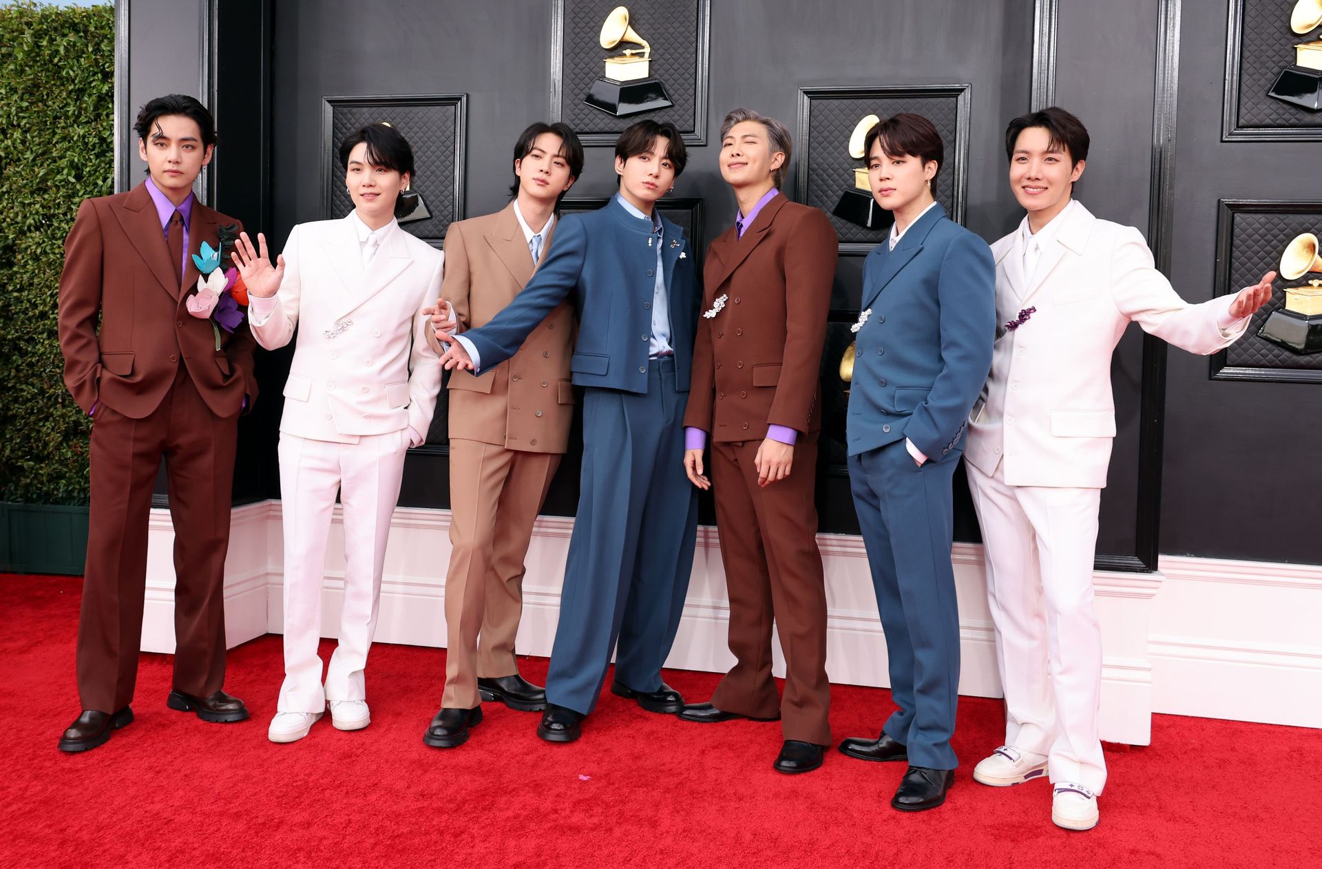 BTS (L-R: V, Suga, Jin, Jungkook, RM, Jimin, and j-Hope) stand in colorful Louis Vuitton suits on the Grammy's red carpet
