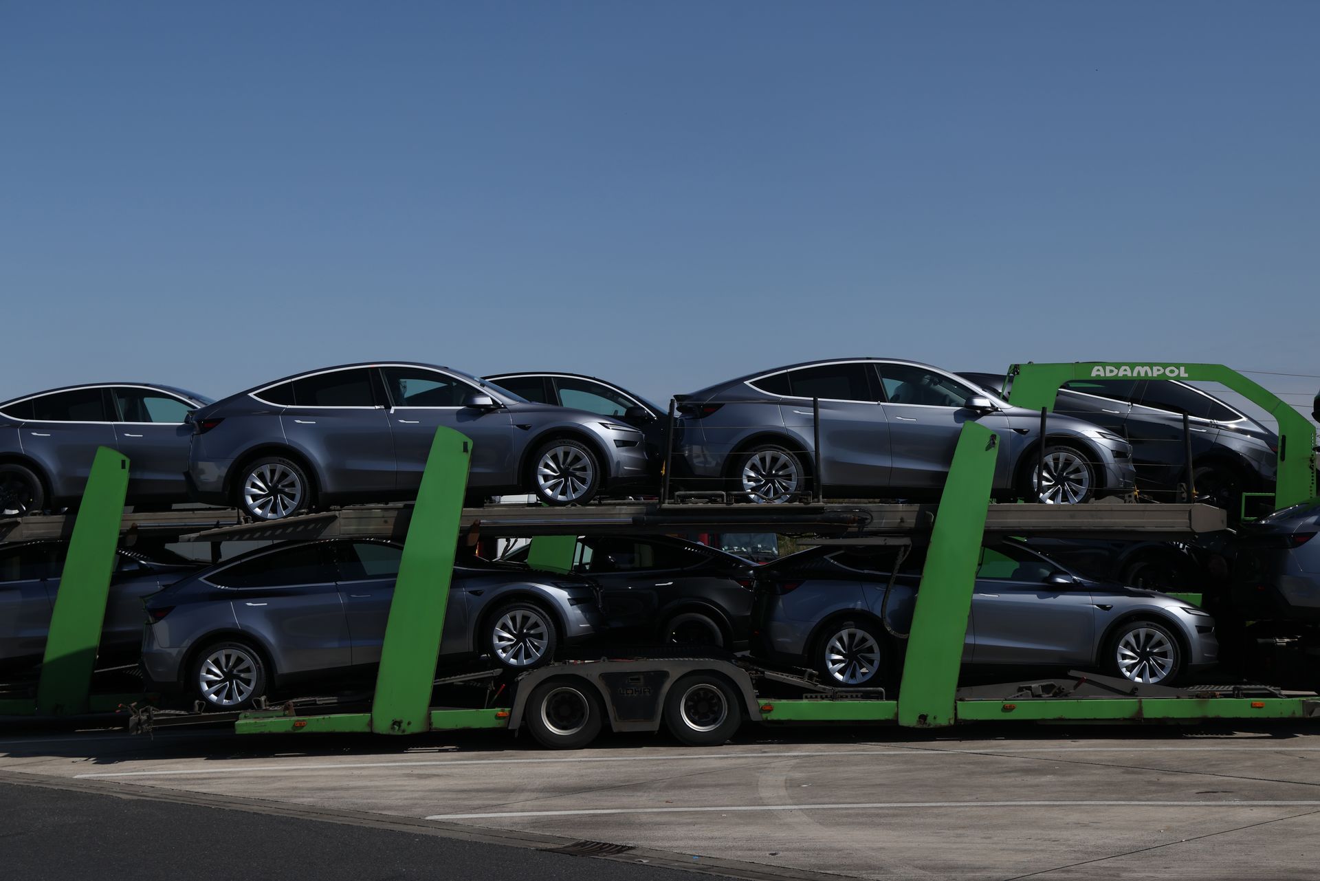 Silver Model Y Teslas sit on a flatbed delivery truck