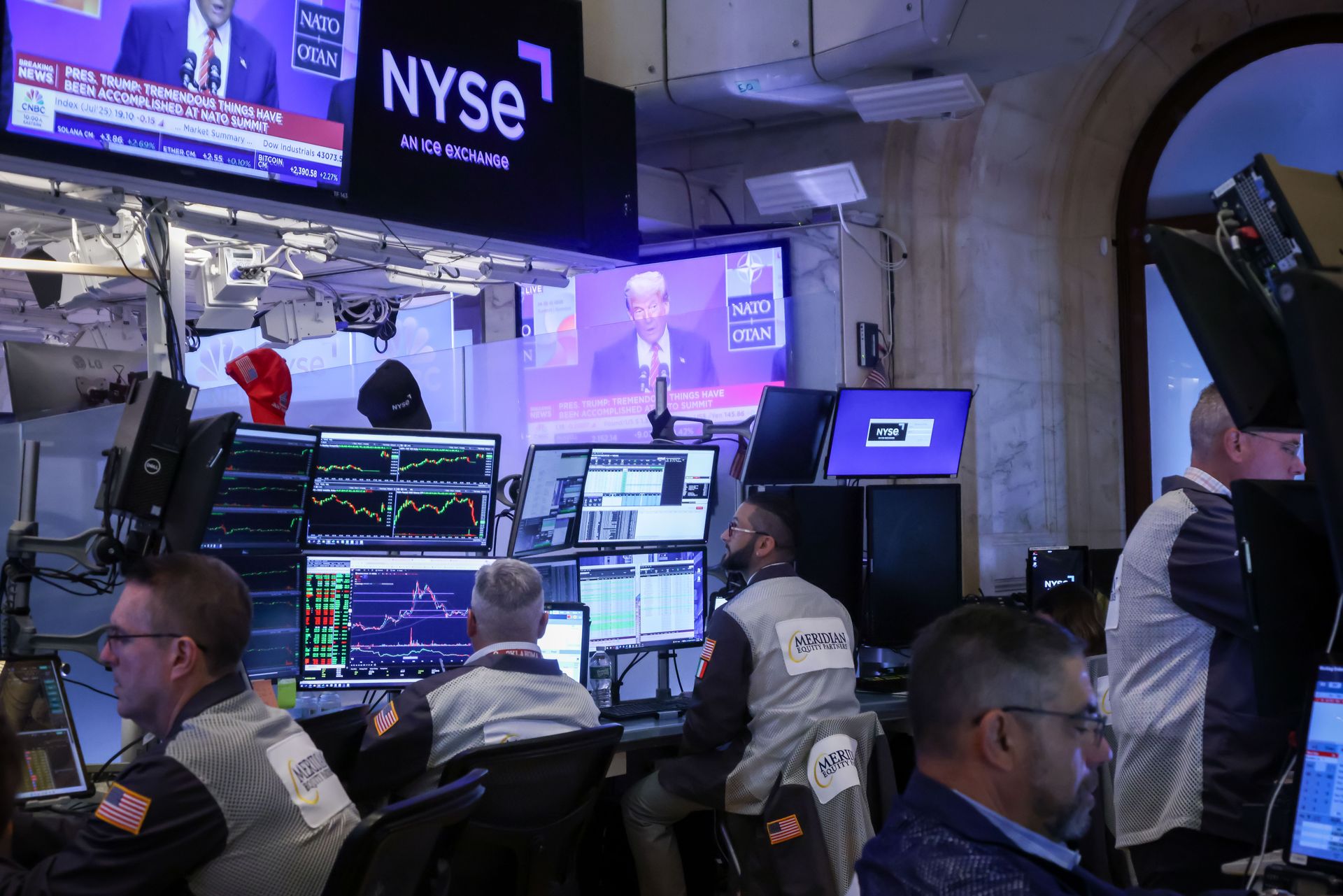traders on sit in front of screens on the floor of the NYSE